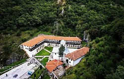 Српски Православни Манастир Света Тројица Пљевља - Архитектонски детаљи главног манастирског објекта подно брда Голубиња са препознатљивим звоником и традиционалним црквеним куполама које доминирају пејзажом изнад града Пљеваља у Црној Гори  Приказ манастирске порте и спољашњих објеката укључујући старе манастирске конаке са дрвеним елементима и камену фасаду храма окупану јутарњим сунцем током летњих месеци