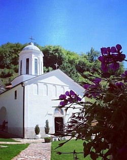 Православни Манастир Свете Тројице Пљевља - Спољашњост главног храма Манастира Свете Тројице у Пљевљима са погледом на средњовековну архитектуру и беле камене зидове подно брда Голубиња