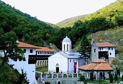 Манастир Српске Прaвославне Цркве Свете Тројице Пљевља - Панорамски приказ манастирског комплекса Свете Тројице у Пљевљима окруженог зеленим падинама и високим дрвећем током сунчаног летњег дана